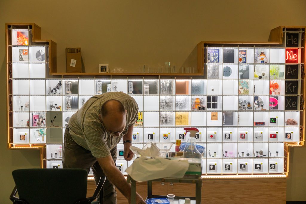 UConn chemistry department head Christian Brückner puts some of the items resembling elements in the interactive periodic table display being installed in the Chemistry Building
