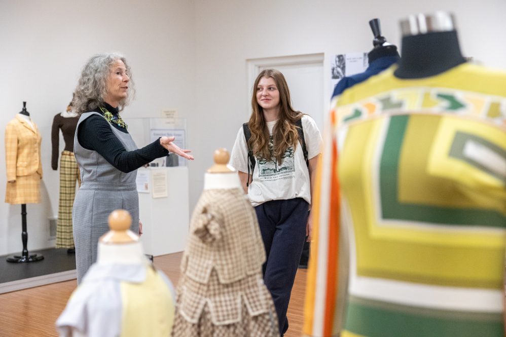 Susan Jerome, curator of the exhibit on display in the Jorgensen Gallery celebrating the UConn Women’s Center’s 50th anniversary, explains some of the items’ histories to UConn student Zoe Orie in the exhibit.