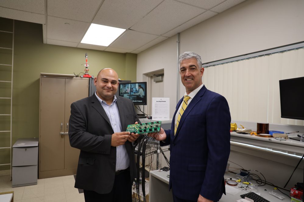Caption: Prof. Bazzi from UConn (left) with Mr. Aslanidis from Ward Leonard (right) along with the first prototype of the converter that is subject of their collaboration.