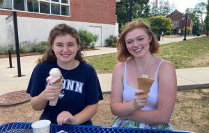 Two high school students face the camera, smiling and holding ice cream cones.