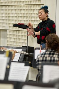 Janet Kim, assistant professor of music, leads a wind ensemble rehearsal
