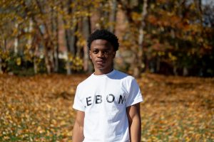 Aime Mulungula standing outdoors in a "Lebon" t-shirt.