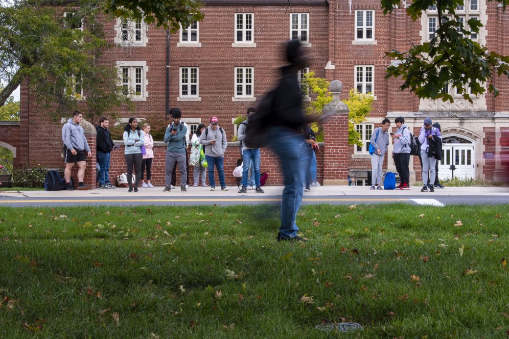 Students in motion along Route 195 in front of Whitney Hall.