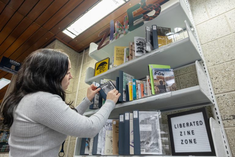Jenna Esposito, a student worker for the archives in Homer Babbidge Library, goes through the zines on display in the Liberated Zine Zone on Level B of the library on Nov. 17, 2022