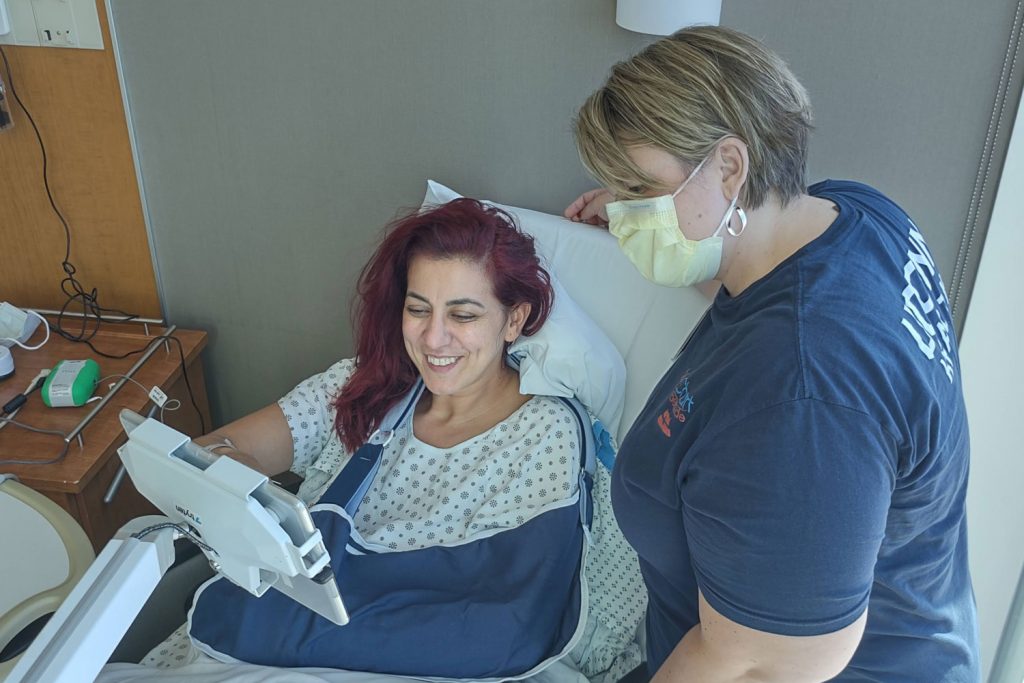 Nurse at bedside with patient using tablet