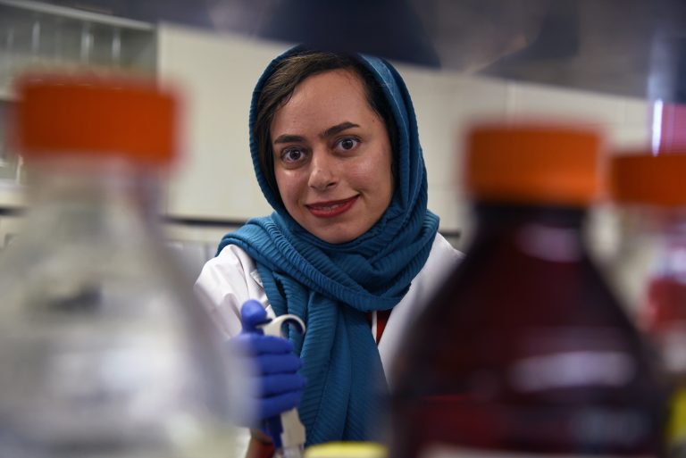 Manije Darooghegi Mofrad smiles in a lab while pipetting