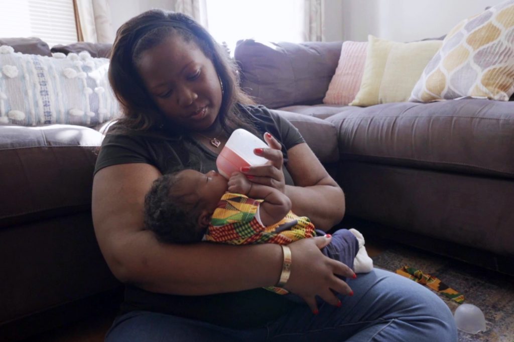 Photo of Daisha Dillon feeding her baby daughter with a bottle