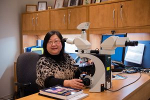 Dr. Qian Wu at a microscope