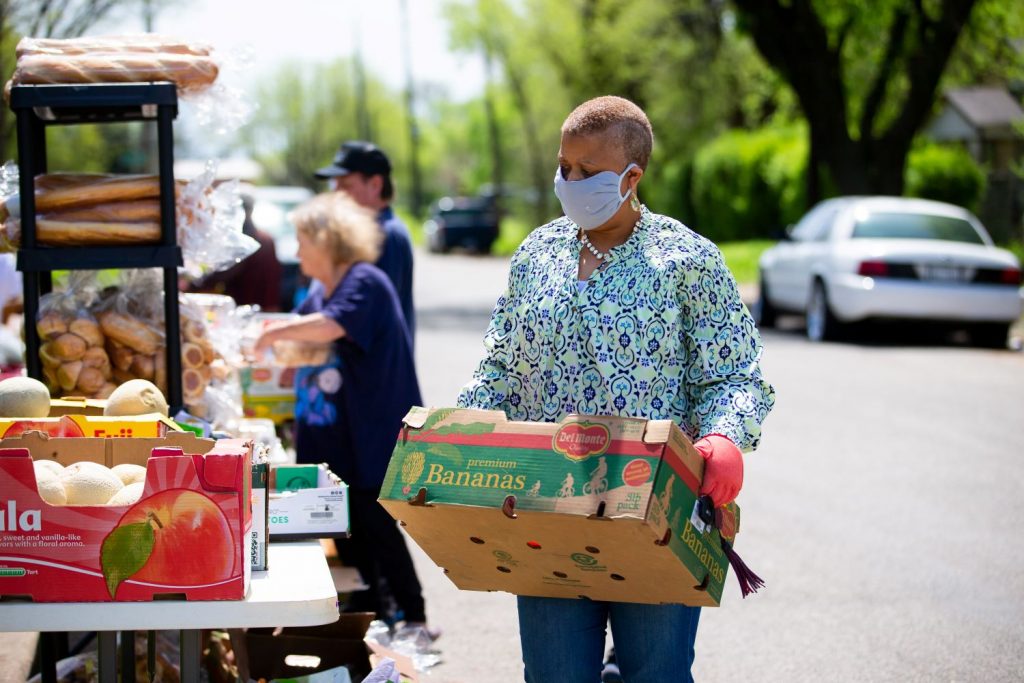 woman carrying a box of banas