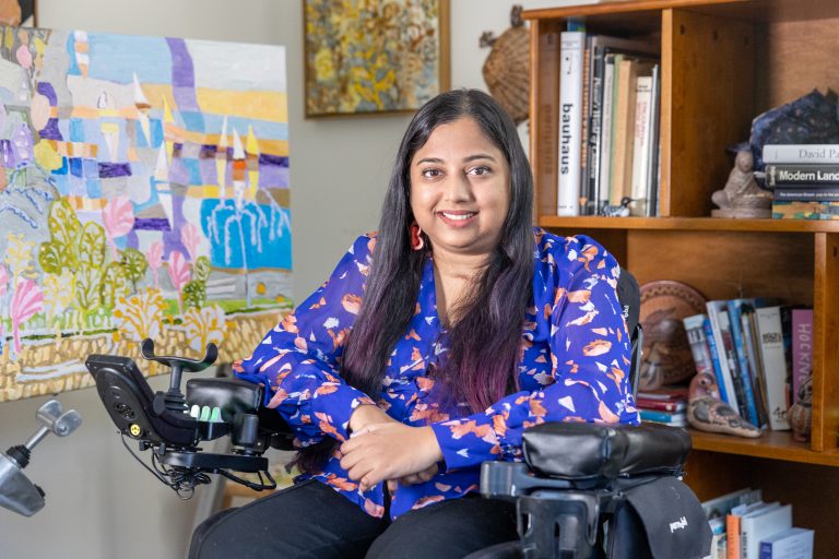 Arpita Kurdekar, an integrated studies Ph.D. candidate in both the School of Fine Arts and the School of Engineering at UConn, poses for a photo among her artwork displayed in her apartment in Storrs