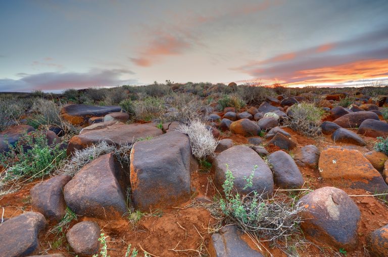 Sunrise over a barren, rocky landscape, namely the Karoo Basin in South Africa.