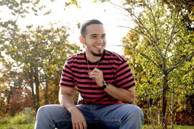 Diverse smiling male wearing striped shirt.