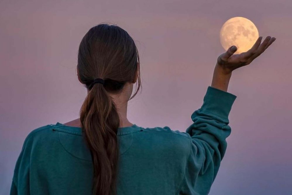 a student "holding" the moon in her palm