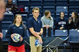 student workers working at a home uconn volleyball game holding volleyballs