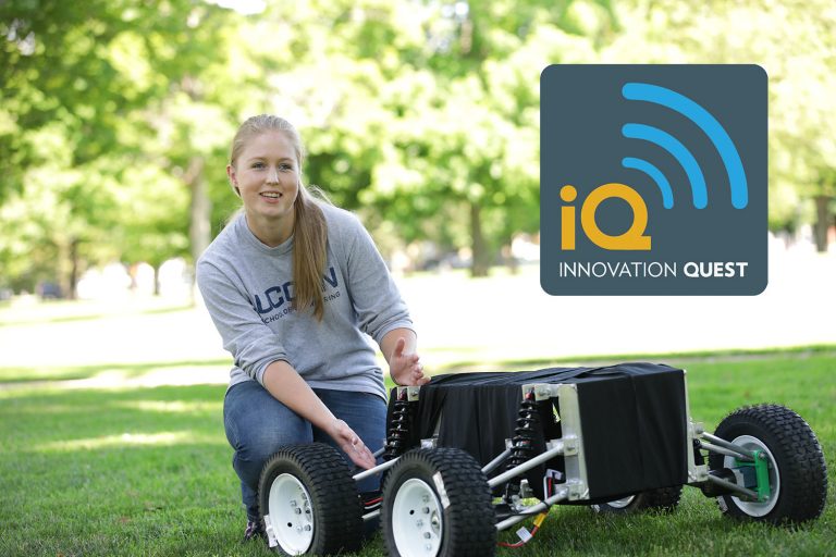 Emily Yale '21, who turned her Innovation Quest proposal into a thriving business, works on lawn equipment on a sunny day, with trees in the background.