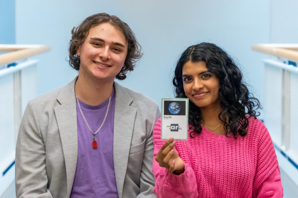 SmartCards AR cofounders Justin Nappi, left, and Sudiksha Mallick pose for a photo with a beta version of one of their product’s flashcards