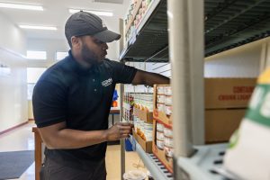 Geraldo White of UConn Dining Services stocks the shelves with goods in the Husky Harvest space near Charter Oak Apartments in Storrs