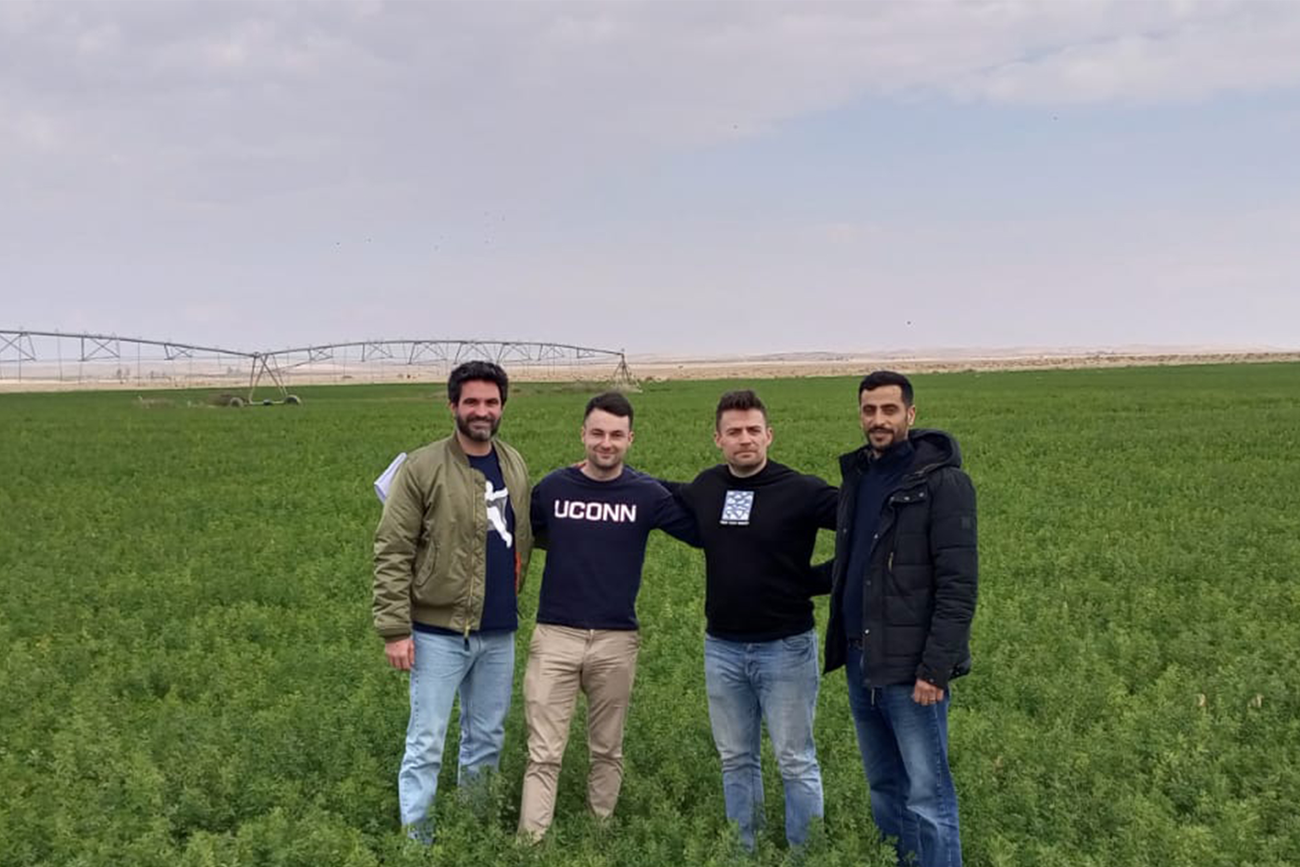 David Coles, Goggins, Ryan Coles, and a Jordanian farmer standing in an alfalfa field.