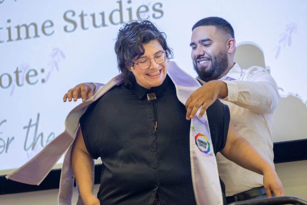 Upcoming UConn graduate J. Wierski, a maritime studies major from UConn Avery Point, accepts a Rainbow Center graduation stole from Michael Vidal, director of diversity and inclusion initiatives, during the Rainbow Center's Lavender Graduation ceremony