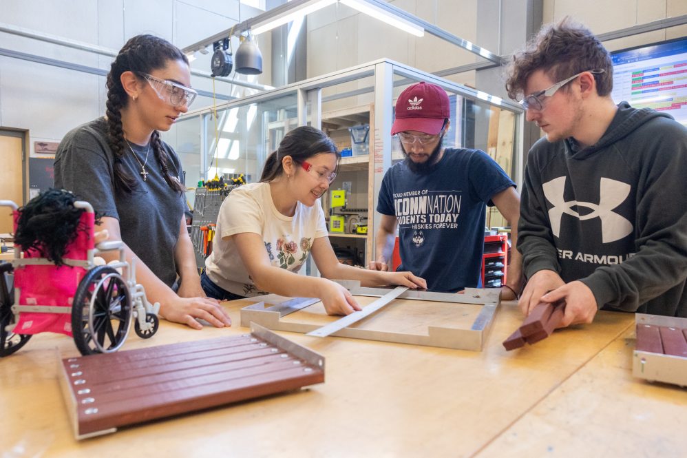 UConn mechanical engineering students, from left, Leila Awad, Kaley Luk, Eddy Ramos and Patrick Miconi work on the prototype of their project for Senior Design Demonstration Day—an affordable, ADA-compliant, sustainably produced, easy-to-assemble accessibility ramp—in the Innovation Zone in the Peter J. Werth Residence Tower