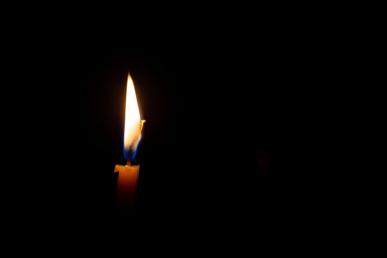 A burning candle isolated in darkness.