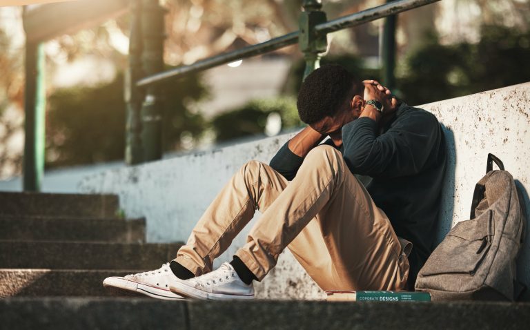 Student, mental health and depression with anxiety, burnout and sad for exam results, fail or mistake while sitting outdoor. Young man, stress and tired and depressed on university or college campus.