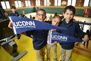 Three students gather with UConn banners.