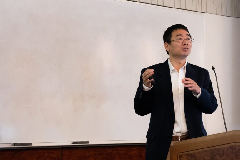 Luyi Sun standing in front of a white board in a lecture hall