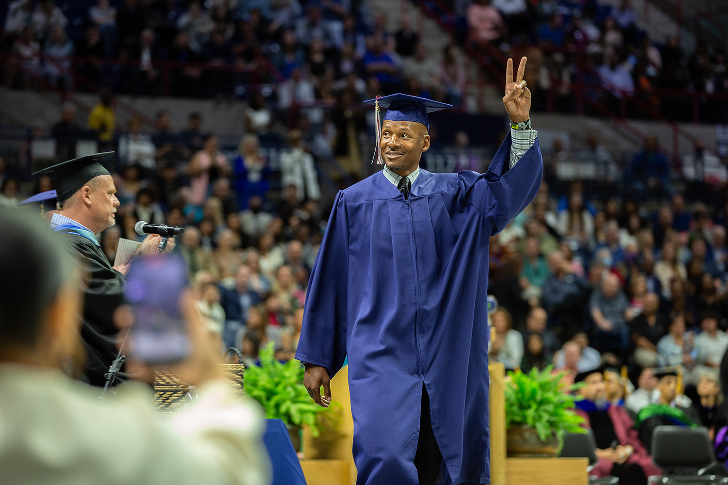 Ray Allen gives peace sign while walking across floor during commencement.
