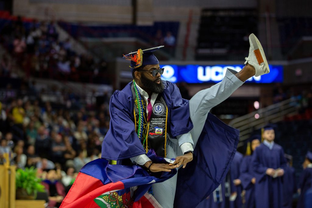 A graduate kicks foot in the air during commencement.