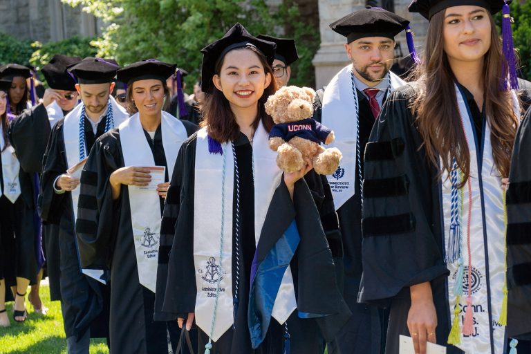 UConn Law graduate with teddy bear in commencement procession