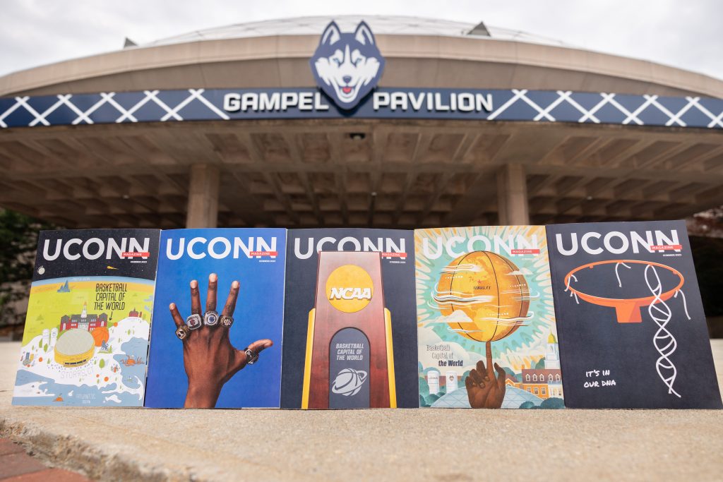 The five covers of the summer 2023 edition of UConn Magazine sit in front of Gampel Pavilion