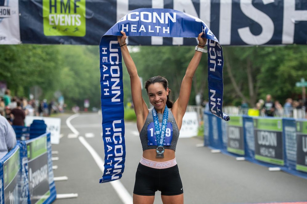 runner with medal holds finish line above her head