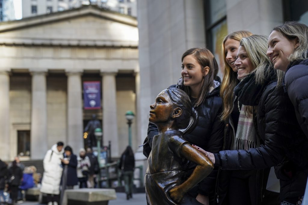 A group of women pose with the 'Fearless Girl' statue after a ceremony to unveil the statue's new location across from the New York Stock Exchange, December 10, 2018 in New York City.