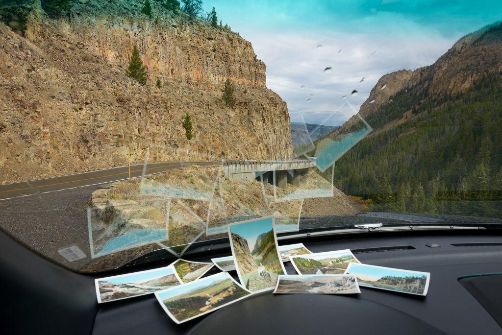 Vintage postcards by Frank J. Haynes sit on the dashboard of a vehicle facing Kingman Pass in Golden Gate Canyon