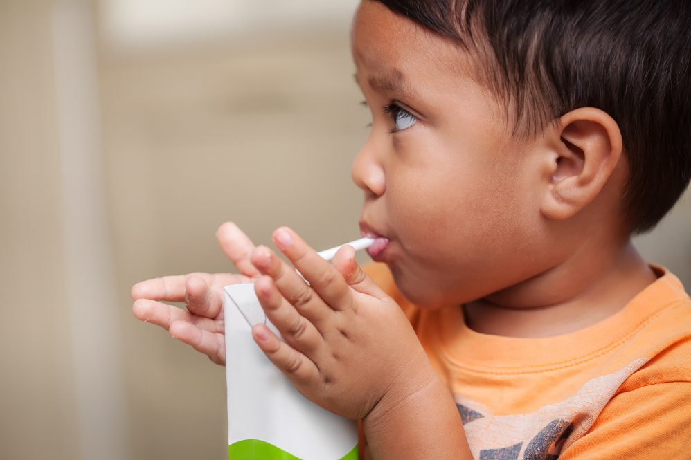 A young boy drinks milk through a straw.