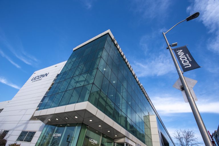 An exterior view of a glass-paneled building in front of a blue sky on the UConn Stamford campus.