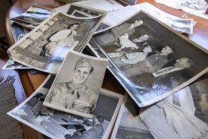 Prints of photos of William Aho from throughout his life sit on a table in his home in Mansfield