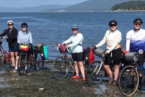 Five cyclists with their bikes on the shore