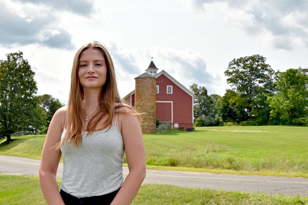 Woman standing in front of red barn
