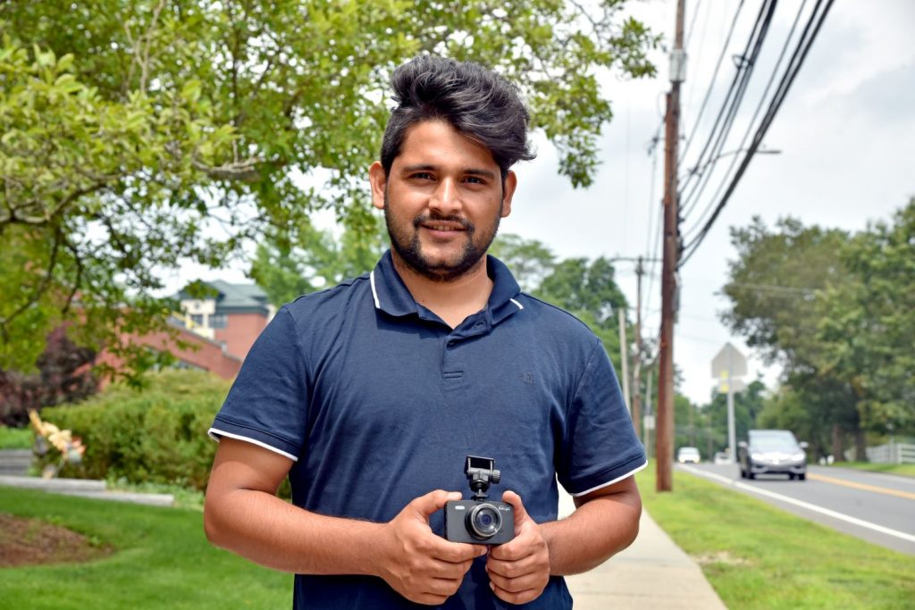 Man stands outside holding camera