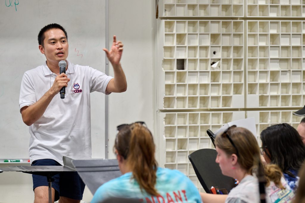 Justin McManus '11 (SFA, ED) '13 MM, director of athletic bands, speaks to the UConn Marching Band during a practice at the Music Building on Aug. 21, 2023. 