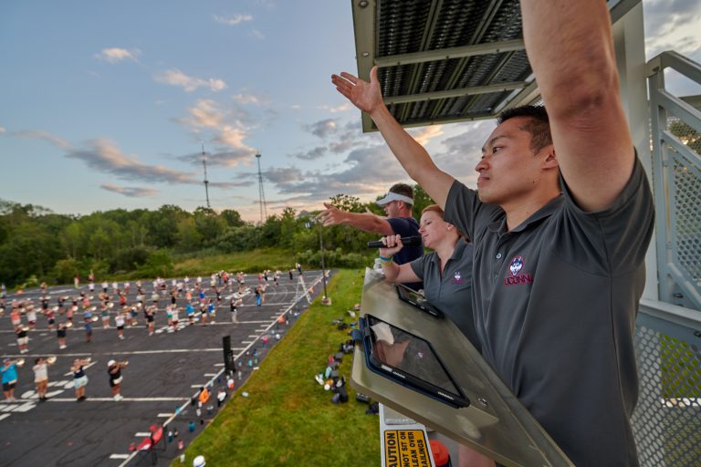 Justin McManus '11 (SFA, ED) '13 MM, right, director of athletic bands, gestures during UConn Marching Band practice at the band field on Aug. 22, 2023.