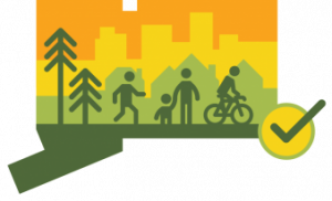 The CT Trail Census Logo, featuring pictographs of several people walking and biking on a trail, flanked by two trees and some urban skylines behind them. The shape of the logo is the shape of the state of Connecticut.