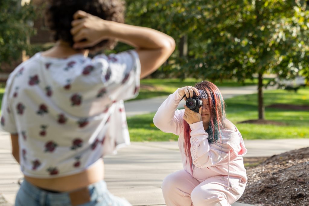 Alexa Udell '24 takes photos of Remi Dupuis '26 for her photography project that highlights transgender students at UConn in the shade garden near the Benton Museum