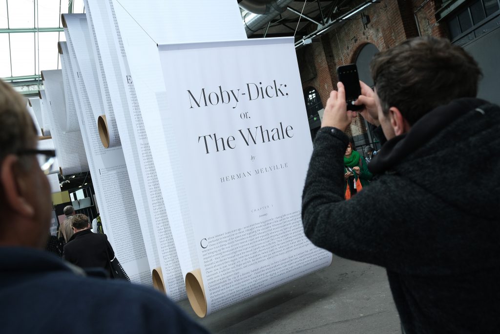 People photograph a display showing a giant copy of Herman Melville's novel "Moby-Dick."