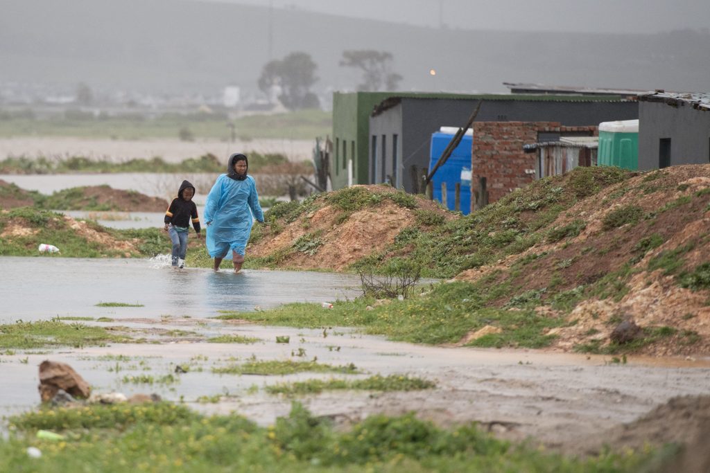 A woman and child walks through water and mud during heavy flooding as a result of a storm in Sandvlei, close to Somerset West on September 25, 2023.