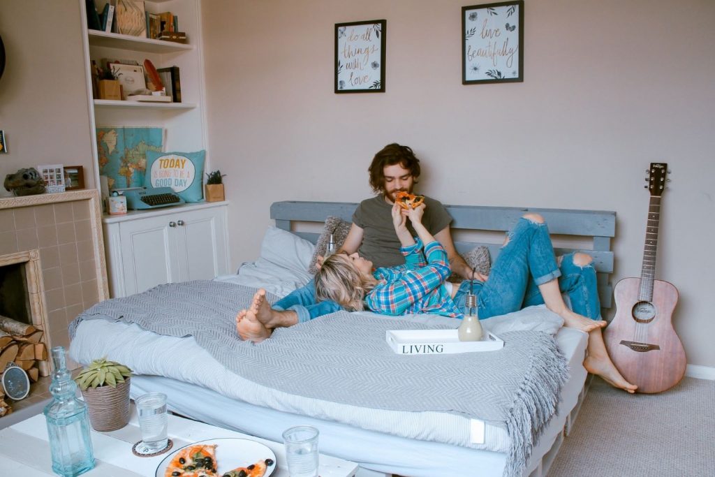 Couple eating pizza on a bed