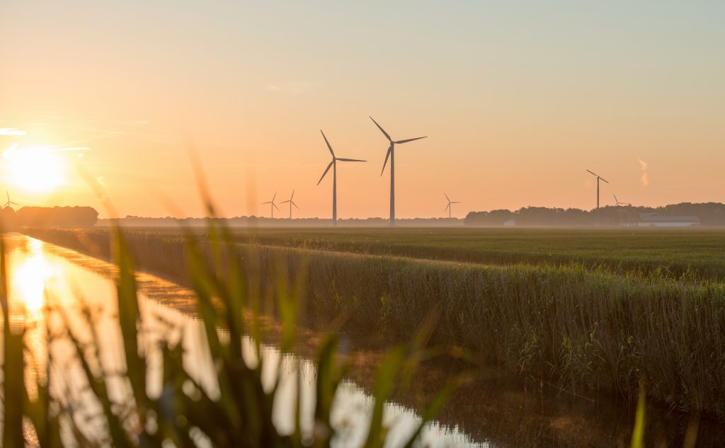 Dawn over a canal in spring with wind turbines in the background.