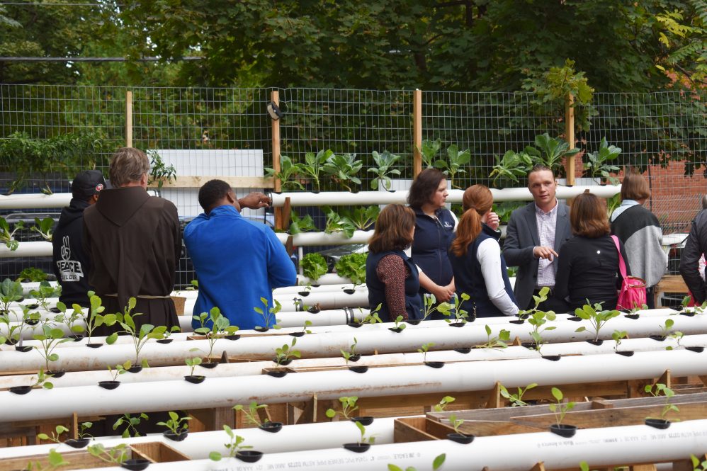 At right, Christian Heiden '20 (CAHNR), founder of Levo International, leads a tour of the micro-farm his startup built on Garden Street in Hartford's North End.